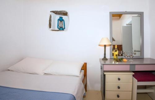 a bedroom with a bed and a dresser with a mirror at Two little houses with panorama view in Kýthira