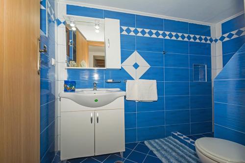 a blue tiled bathroom with a sink and a toilet at Two little houses with panorama view in Kýthira