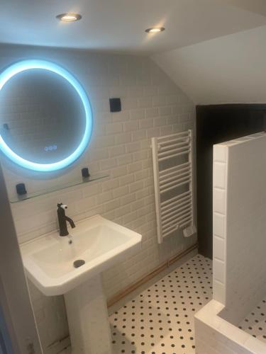 a bathroom with a white sink and a blue light at Nid douillet in Pont-Audemer