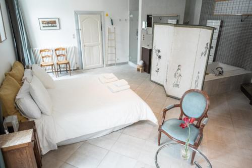 a bedroom with a large white bed and a chair at Maison Harmonie in La Châtre