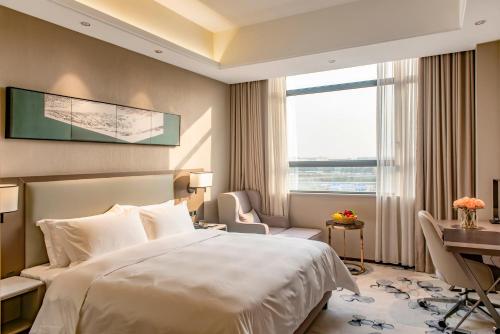 a hotel room with a bed and a desk and a window at Guangzhou Southern Airlines Pearl Airport Hotel- Free shuttle bus to airport in Guangzhou