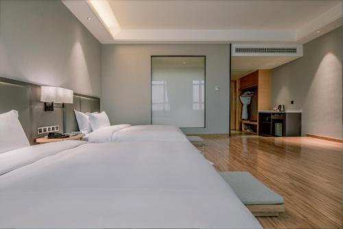 a large bedroom with two white beds and a hallway at Guangzhou Southern Airlines Pearl Airport Hotel- Free shuttle bus to airport in Guangzhou