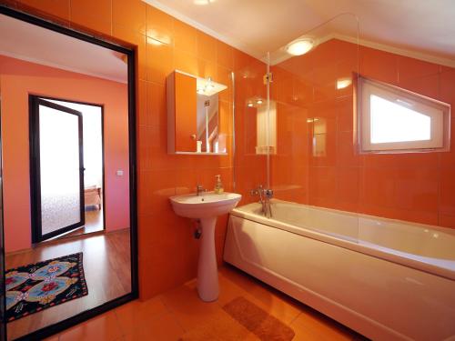 a bathroom with orange walls and a sink and a tub at Vila Roberta in Buşteni