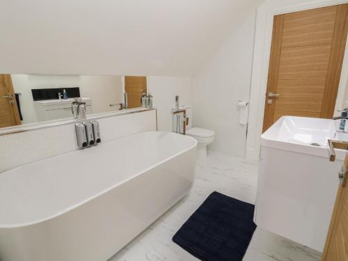 Baño blanco con bañera y lavamanos en Kerry Cottage, en Holywell