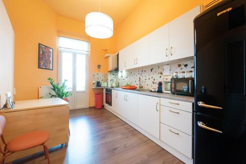 eine Küche mit weißen Schränken und einem schwarzen Kühlschrank in der Unterkunft #Fandango Gorgeous Neoclassical Apartment in Thessaloniki