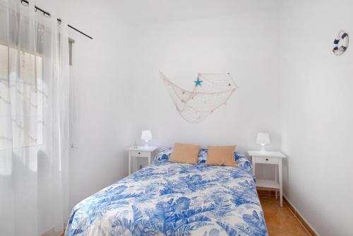 ein Schlafzimmer mit einem Bett mit einer blau-weißen Bettdecke in der Unterkunft Atico Las Arenas in Arico