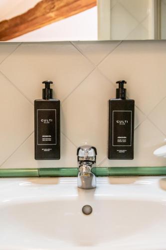 two bottles of soap sitting on a bathroom sink at Casa Isolani Charms Rooms Santo Stefano in Bologna