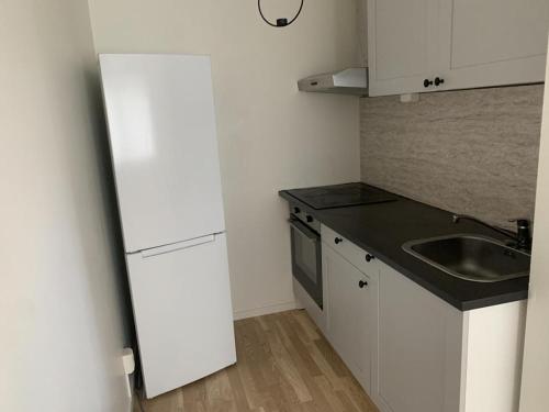 a kitchen with a white refrigerator and a sink at Inviting Apartment in Kista Stockholm in Stockholm