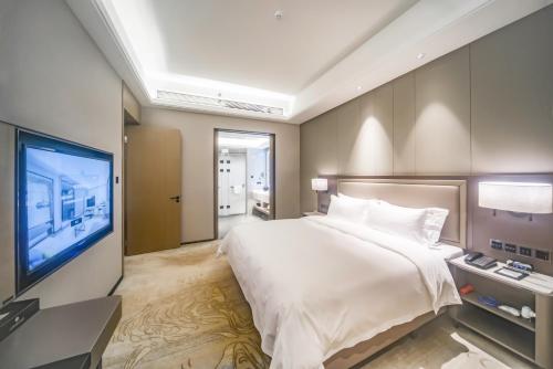 a bedroom with a large bed and a flat screen tv at Guangzhou Southern Airlines Pearl Airport Hotel- Free shuttle bus to airport in Guangzhou