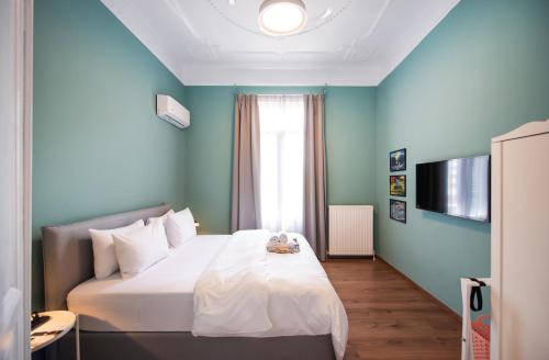 a bedroom with a white bed with a blue wall at Fandango by halu!, Gorgeous Neoclassical Apartment next to Metro station in Thessaloniki