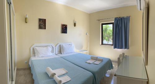 een slaapkamer met een blauw bed en handdoeken bij FLOR DO VALE - APARTAMENTOS TURISTICOS in Guia