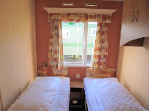 two beds in a small room with a window at 6 Berth Sealands Ingoldmells Central heated (Carlton) in Ingoldmells