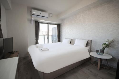 a bedroom with a large white bed and a table at Seiryu Tsutenkaku in Osaka