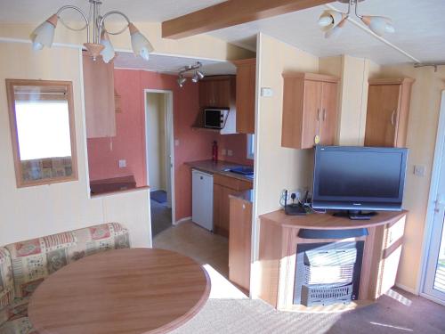 a kitchen with a table and a tv in a room at 6 Berth Sealands Ingoldmells Central heated (Carlton) in Ingoldmells