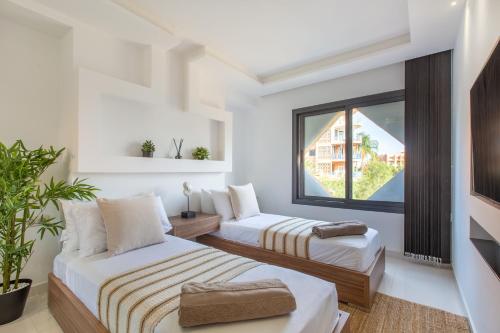 two beds in a room with a window at Escale VIP Cœur de l'Hivernage en Face du Sofitel in Marrakech