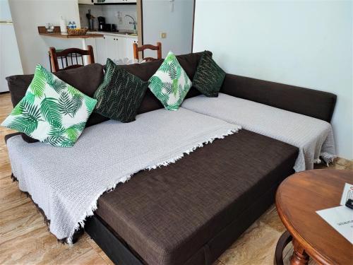 Un sofá marrón con almohadas verdes y blancas. en Awesome Apartment, en Puerto del Rosario
