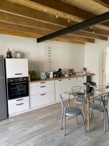 a kitchen with white cabinets and a table with chairs at Le Refuge des Etoiles Gîte et Spa in Zutkerque