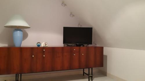 une télévision sur un meuble en bois avec une lampe dans l'établissement Gite de Kervao, Hortensias avec jardin privatif, Plage 700 m, à Ploudalmézeau