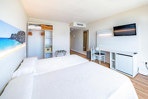 a bedroom with two beds and a desk with a tv at Seramar Hotel Comodoro Playa in Palmanova