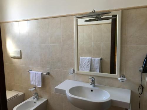 Un baño con lavabo, espejo e inodoro. en Pescasubacquea, en Crotone