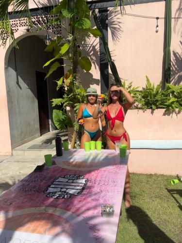 two women in bikinis standing next to a table at Clandestino Hostel Canggu in Canggu
