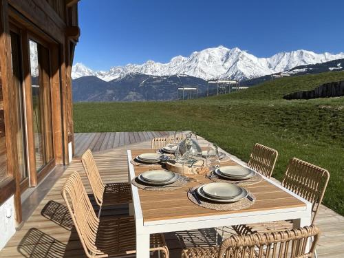 a table on a deck with mountains in the background at Chalet Vue Mont-Blanc imprenable in Combloux