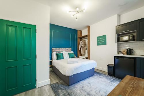 a bedroom with a bed with green doors and a kitchen at Emerald Stays UK at The Adelphi in Stratford-upon-Avon
