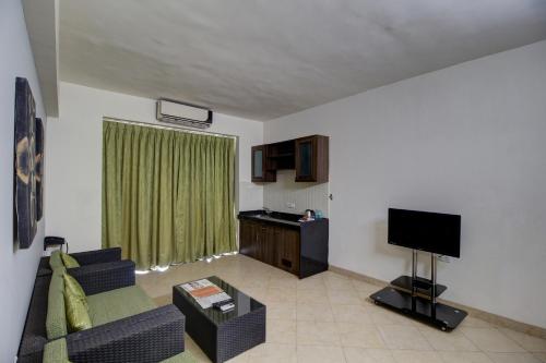 a living room with a couch and a television at Royale Assagao Resort in Assagao