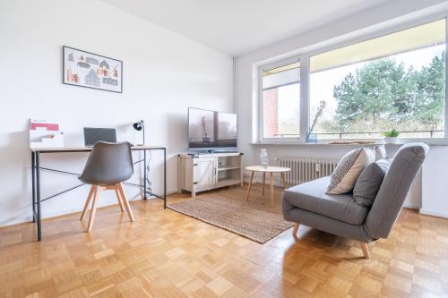 a living room with a chair and a desk at Studioapartment mit Küche und großem Balkon in Flensburg