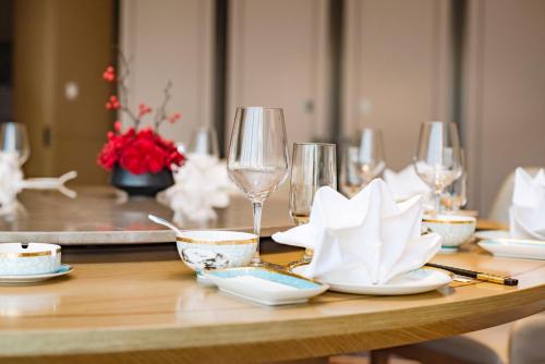 a wooden table with wine glasses and plates on it at Guangzhou Southern Airlines Pearl Airport Hotel- Free shuttle bus to airport in Guangzhou