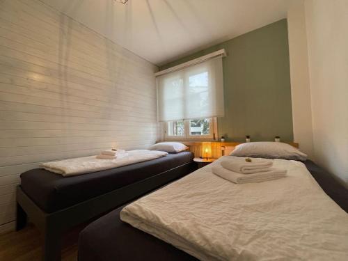 two beds in a small room with a window at No.8 Boutique Apartment in Unterseen