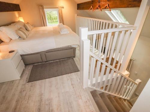 Lee House Cottage في Cheddleton: غرفة نوم بسرير كبير ودرج
