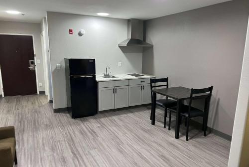 a kitchen with a black refrigerator and a table at Super 8 by Wyndham Lake Charles/Sulphur in Lake Charles