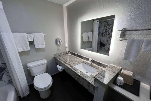 a bathroom with a toilet and a sink with a mirror at Super 8 by Wyndham Lake Charles/Sulphur in Lake Charles