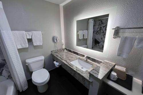 bagno con servizi igienici e lavandino con specchio di Super 8 by Wyndham Lake Charles/Sulphur a Lake Charles