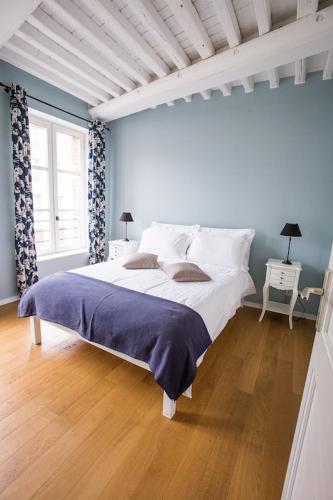 une chambre avec un grand lit blanc avec des murs bleus dans l'établissement Centrally located, refurbished modern flat with views over the historic port, à Honfleur
