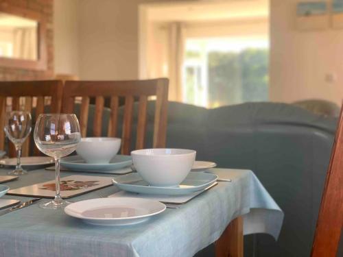 a table with plates and bowls and wine glasses at Bainvalley Cottages, Beautiful North Cottage in Lincolnshire