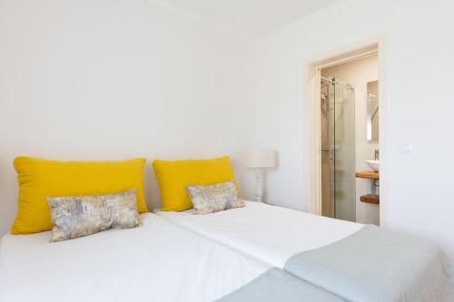 Una cama blanca con almohadas amarillas en un dormitorio en WHome Countryside Charm Near Wedding Venue w/ BBQ Patio, en Torres Vedras