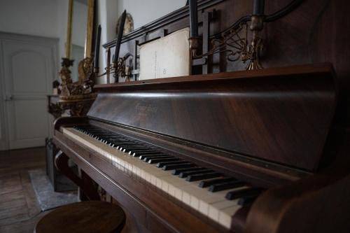an old piano sitting in a room at Maison Harmonie in La Châtre