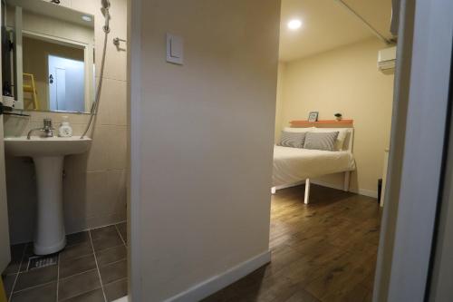 a bathroom with a sink and a mirror and a bed at Just4u Guesthouse in Seoul