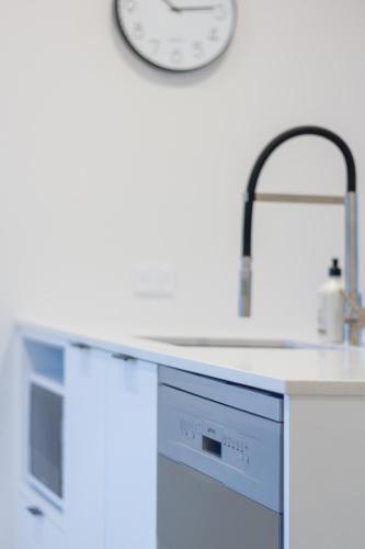 a kitchen with a sink and a clock on the wall at City Lights Retreat with Carpark 2 Bed 2 Bath in Christchurch