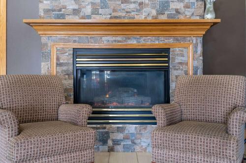 two chairs sitting in front of a fireplace at AmericInn by Wyndham Cedar Rapids North in Cedar Rapids