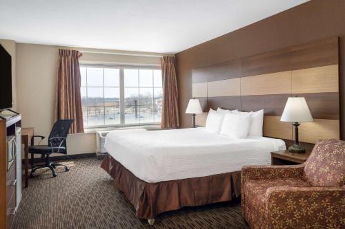 a hotel room with a large bed and a chair at AmericInn by Wyndham Cedar Rapids North in Cedar Rapids