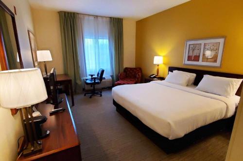 a hotel room with a large bed and a desk at Wingate by Wyndham Uniontown in Uniontown