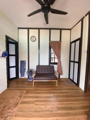 ein Wohnzimmer mit einer Couch und einem Deckenventilator in der Unterkunft Sue Cottage Homestay in Jertih