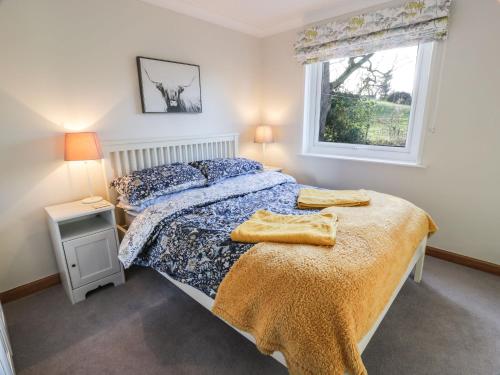 a bedroom with a bed and a window at Millbrook Cottage in Dalbeattie