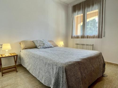 a white bedroom with a bed and a window at Museu Baixos in L'Escala