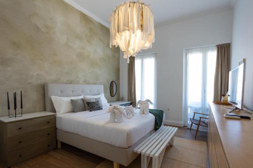 una camera da letto con un grande letto bianco e un lampadario a braccio di Dimora di Stile a Città di Corfù