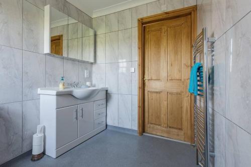 a bathroom with a sink and a mirror and a door at Bainvalley Cottages - The Shamba, sleeps 4 in Lincolnshire