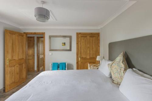 a bedroom with a large white bed and wooden doors at Bainvalley Cottages - The Shamba, sleeps 4 in Lincolnshire